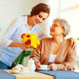 caregiver giving flowers to a senior woman