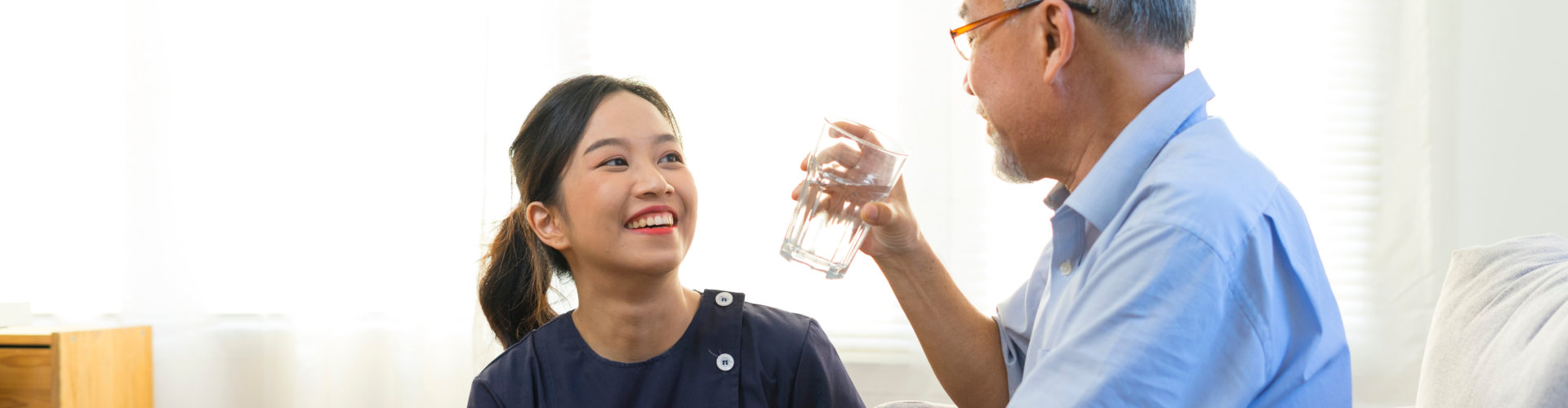 Smiling nurse giving glass of water to senior